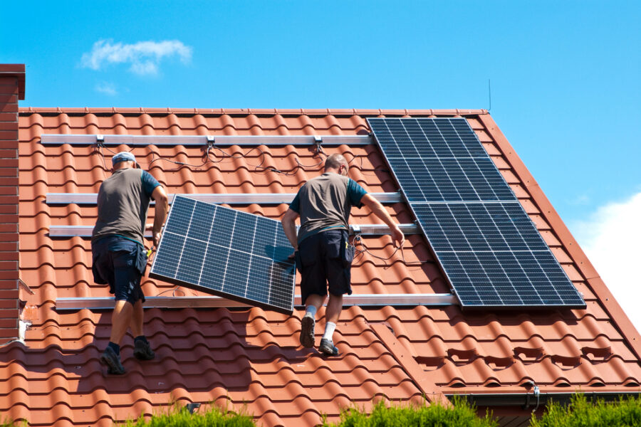 Two men installing solar panels on a roof